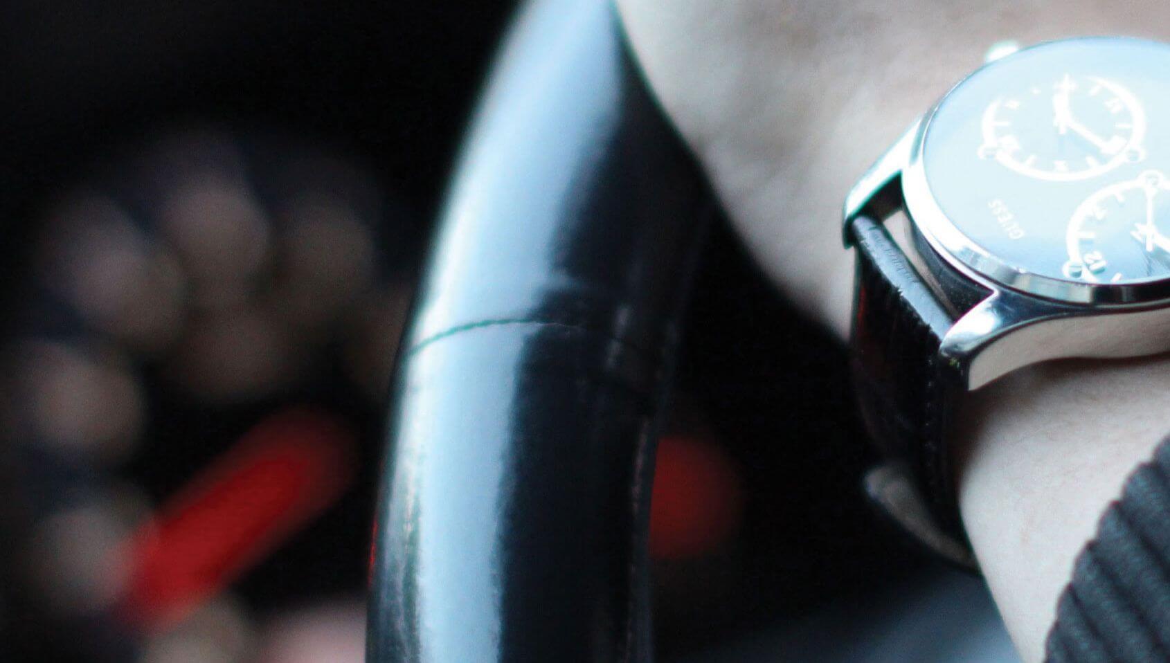 Close up view of a hand on the steering wheel of a vehicle.